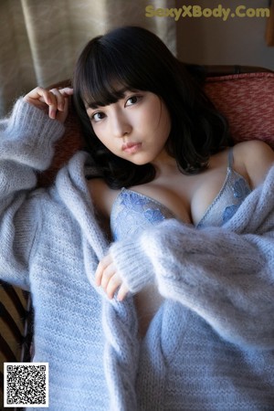 A woman in a blue bodysuit sitting on a chair.