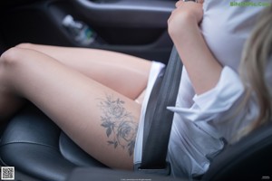 A woman standing in front of a car looking out the window.