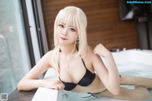 A woman in a black bikini sitting on a ledge.