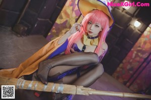 A woman with pink hair sitting on top of a suitcase.