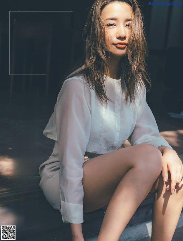 A woman sitting on the ground with her legs crossed.