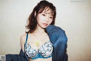 A woman in a blue and white lingerie sitting on the floor.