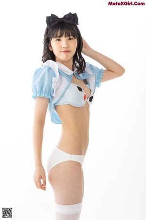 A woman in a blue and white outfit leaning against a wall.
