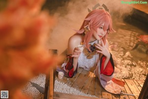 A woman sitting on a wooden bench holding a cup of coffee.