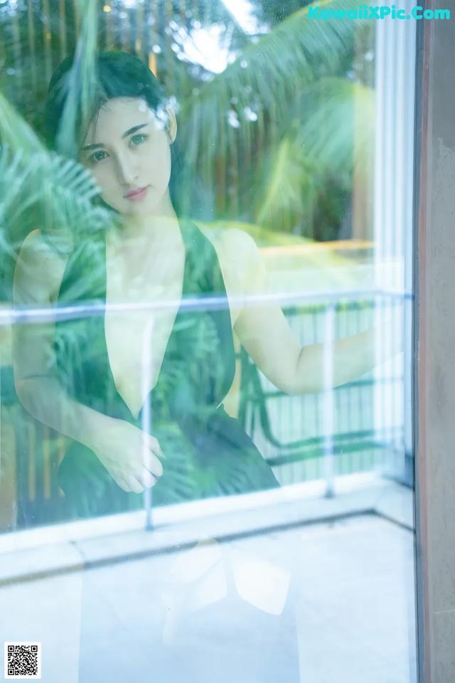 A woman in a green dress looking out of a window.