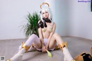 A woman in a costume sitting on the ground next to a plant.