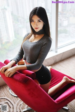 A woman sitting on a window sill next to a window.