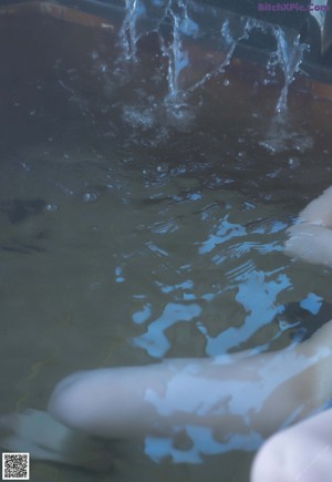 A naked asian woman in a bathtub with water on her body.
