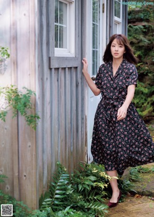A woman sitting on a brick walkway in a garden.