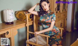 A woman in a blue dress sitting on a wooden chair.