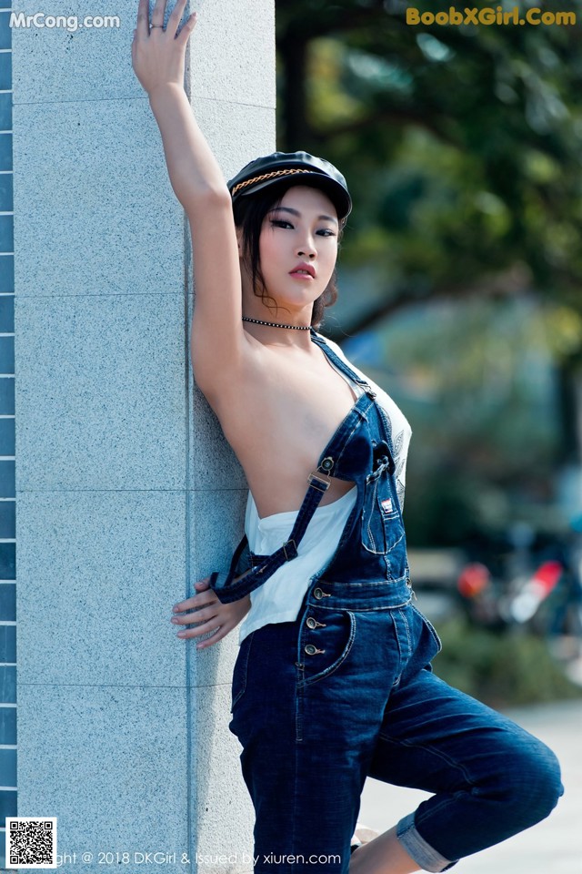 A woman leaning against a wall with her hand on the wall.