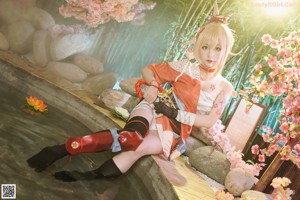 A woman in a kimono sitting on a rock in front of flowers.