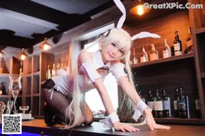 A woman in bunny ears sitting at a bar holding a glass of wine.