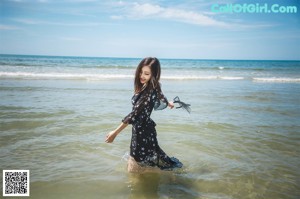 A woman in a pink and blue lingerie posing on a couch.