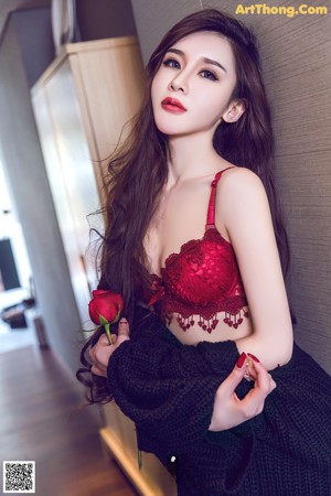 A woman in a red lingerie holding a red rose.