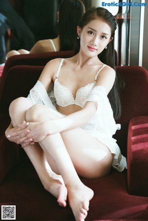 A woman in a school uniform sitting on a bed.