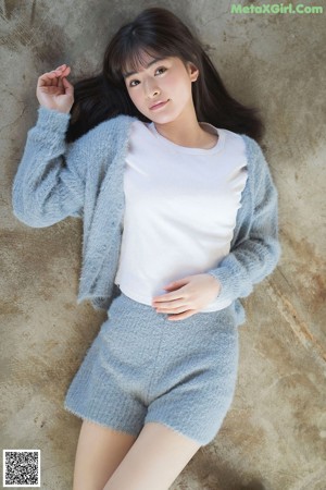 A woman wearing a gray hooded sweater and smiling.
