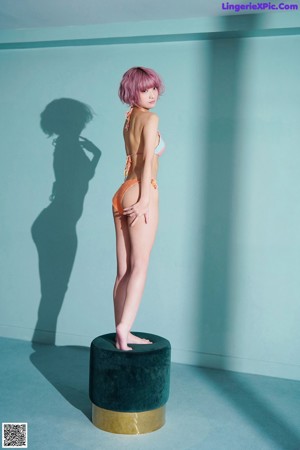 A woman in a bikini and headphones sitting on a table.