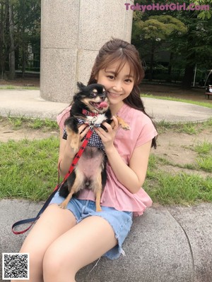 A young girl holding a small dog on a leash.