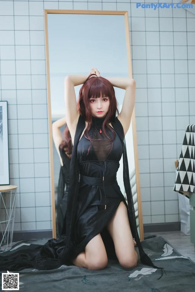 A woman in a black dress sitting on the floor.