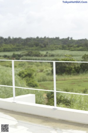 A woman sitting on a ledge with her legs crossed and wearing flip flops.