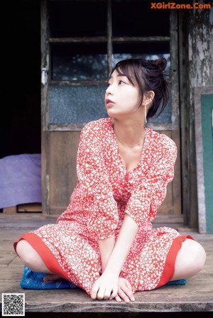 A woman laying on top of a bed next to a window.