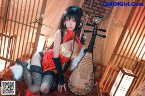 A woman in a red and black outfit holding a musical instrument.