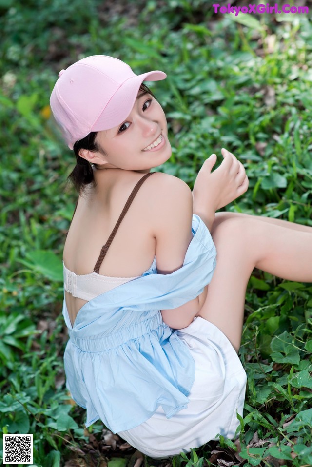A woman in a pink hat is sitting in the grass.