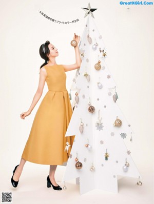 A woman in a green dress sitting on a pile of presents.