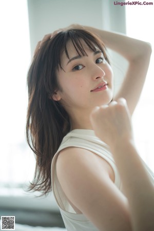 A woman leaning against a wall with her arms outstretched.