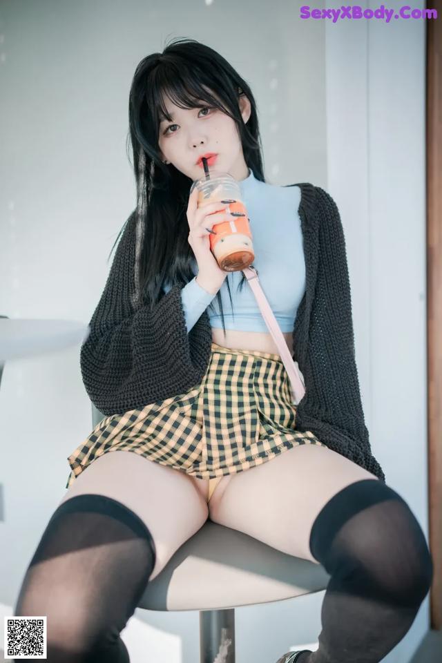 A woman sitting on top of a stool holding a drink.