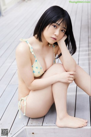 A woman in a yellow bikini sitting on a bench.