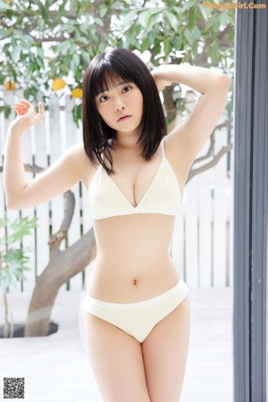 A woman in a yellow bikini sitting on a bench.