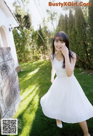 A woman in a white dress standing in a field.