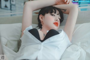 A woman in a white shirt and black stockings laying on a bed.