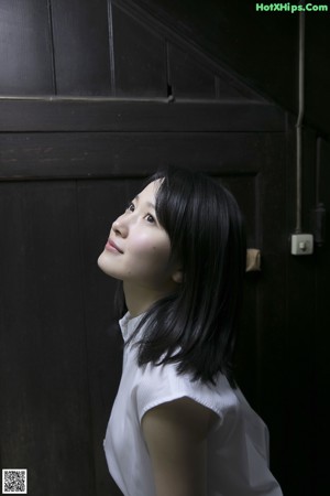 A woman leaning against a wall in a garden.