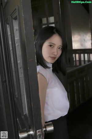 A woman standing in front of a white wall.