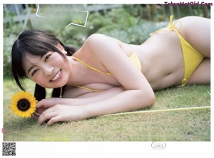 A woman in a yellow bikini and a straw hat.