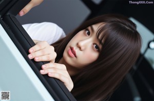 A woman in a school uniform sitting on the ground.