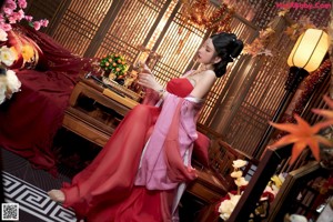 A woman in a pink dress sitting on a table.