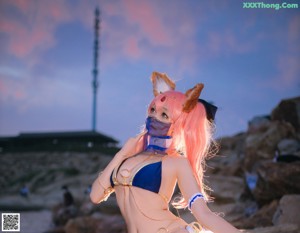 A woman in a bikini sitting on top of a rock.