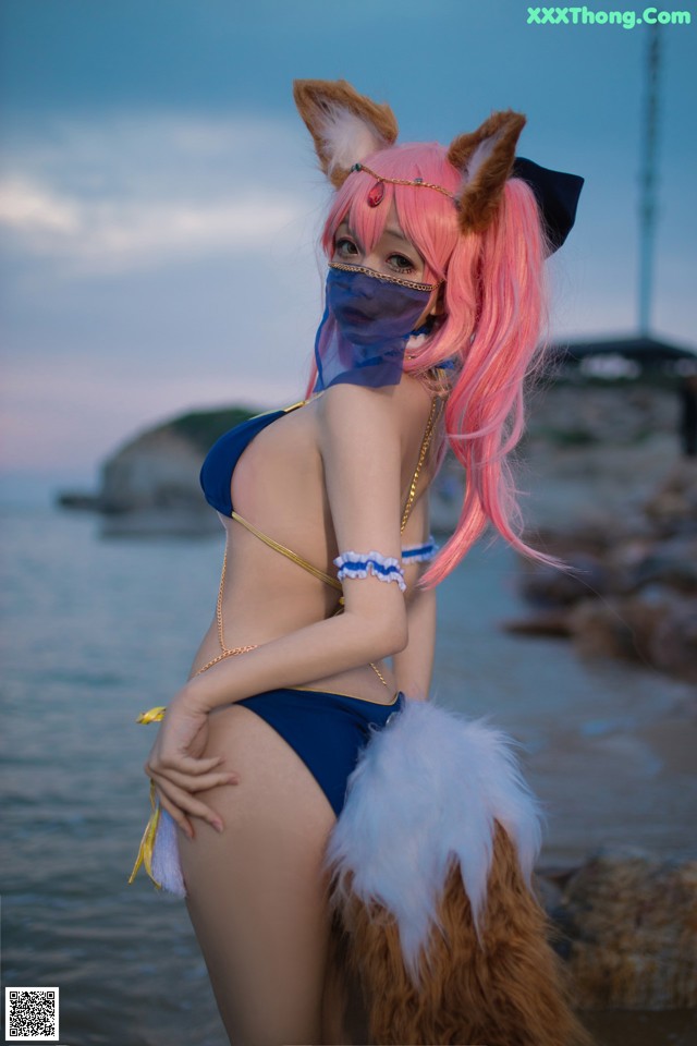 A woman in a bikini with pink hair and a fox mask.