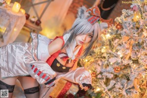 A woman sitting on the floor in front of a Christmas tree.