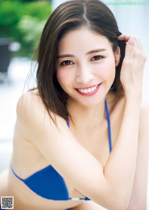 A woman sitting on the floor in a white shirt and blue bra.